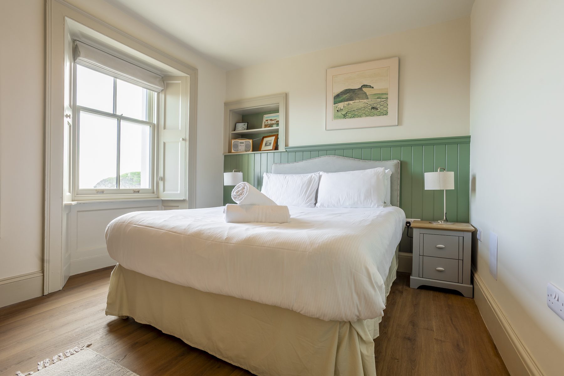Bedroom with panelled headboard wall and window