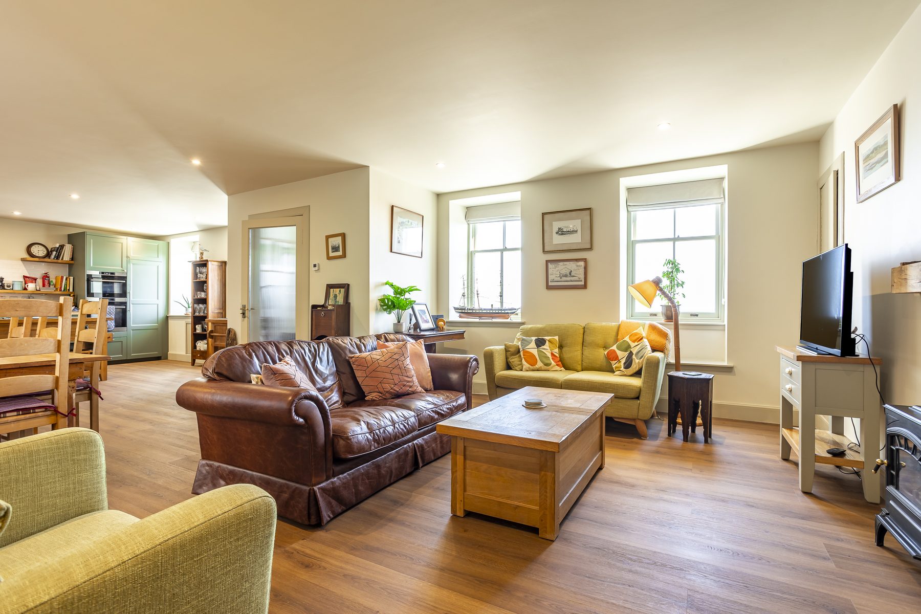 Open-plan living room with oak floors and sofas